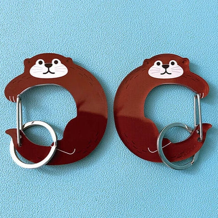 Two cartoon-style otter-shaped carabiners on a blue background
