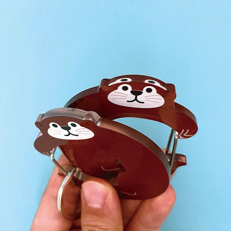 Two brown animal-shaped keychains held against a light blue background