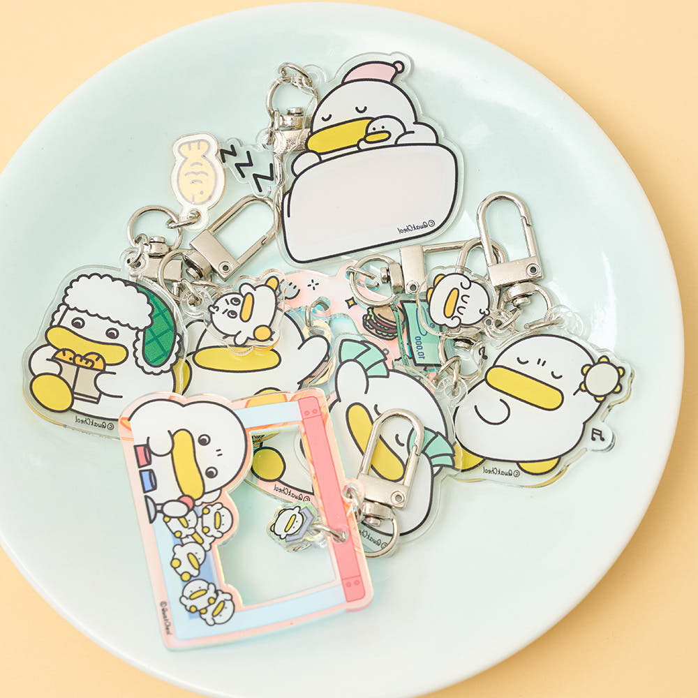 Collection of cartoon duck keychains on a white plate with a beige background